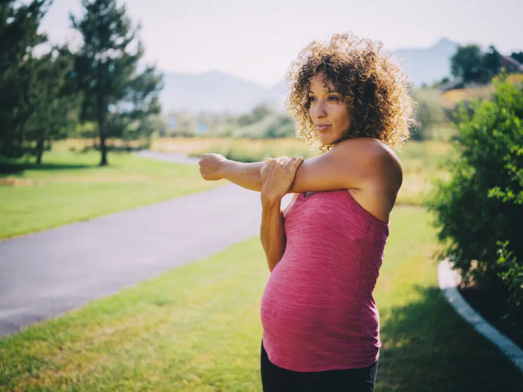 A pregnant woman jogging in a park.