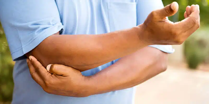 Tennis Elbow - man in blue shirt holding elbow