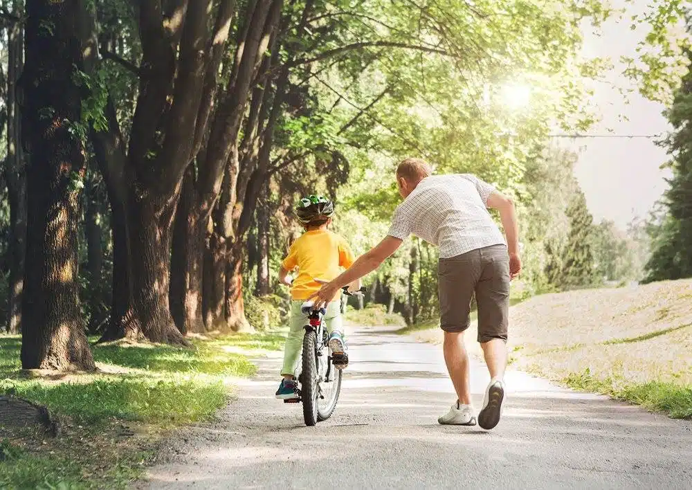 Father helping his son ride a bicycle Willow Chiropractic