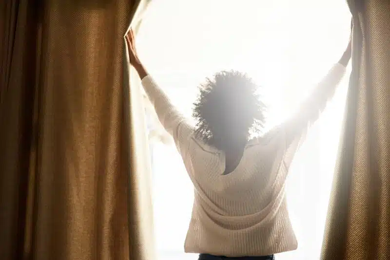 woman opening her curtains Willow Chiropractic