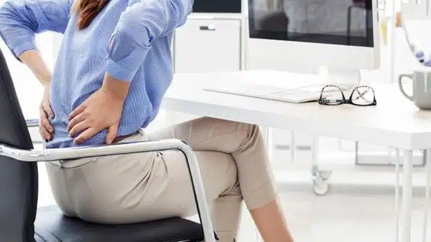 Managing Back Pain - Lady holding lower back in chair willow chiropractic pain relief